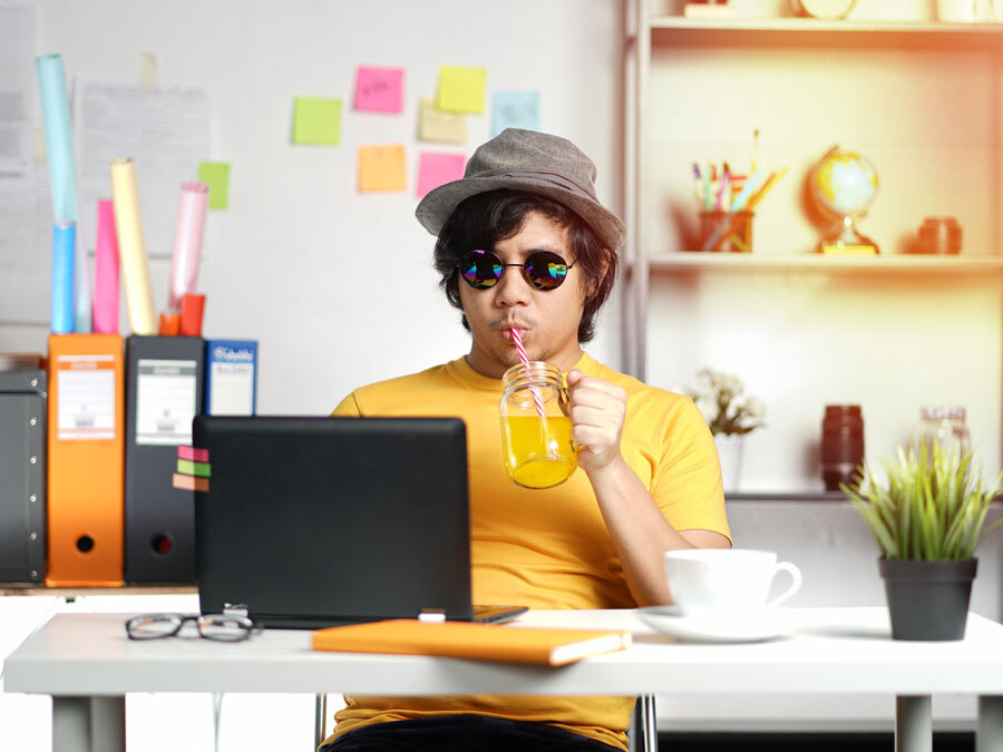 Ein Mann sitzt am Schreibtisch und macht die Urlaubsvertretung für seine Kollegin.