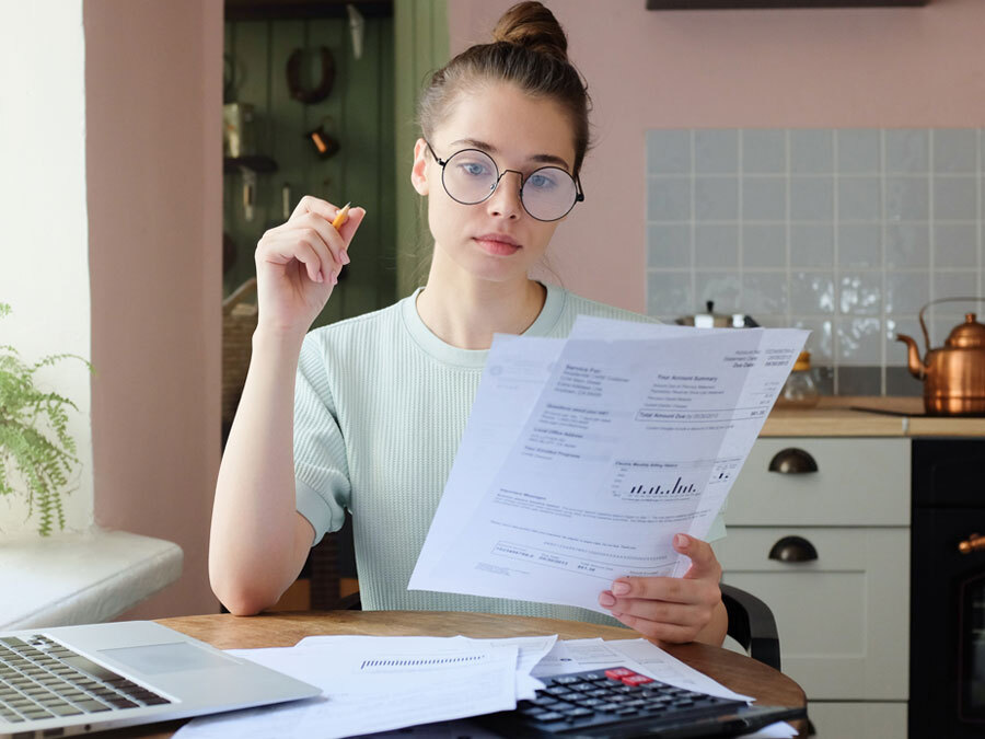 Eine Frau sitzt im Homeoffice in der Küche und liest ein Dokument.