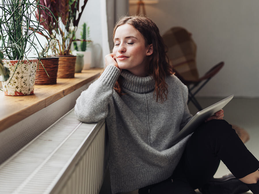 Eine Frau sitzt an einer Heizung.