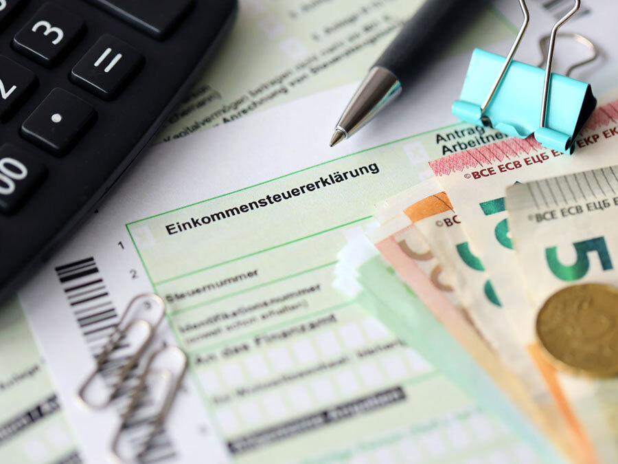 Die Steuererklärung 2021 liegt zusammen mit Büroutensilien auf einem Schreibtisch.