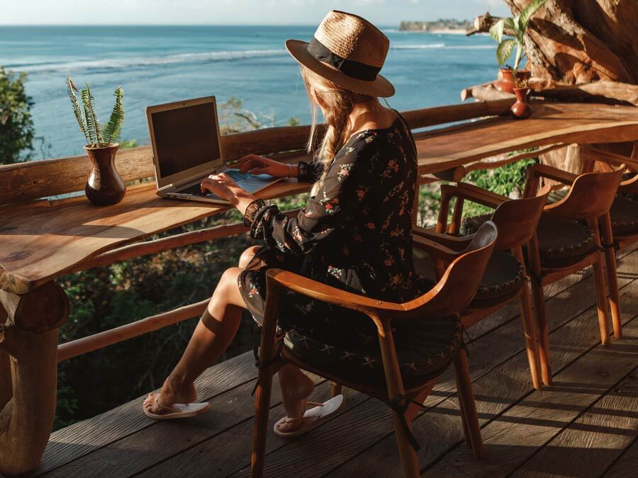 Eine Frau befindet sich in einer Workation und arbeitet am Meer.